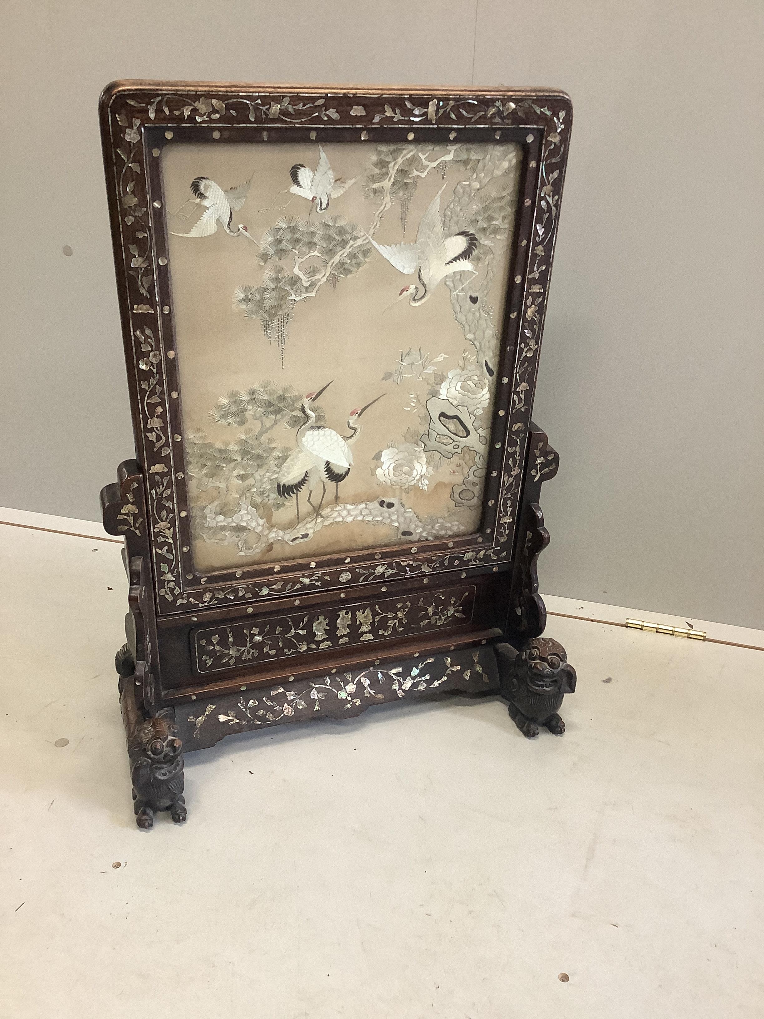 A Chinese mother of pearl inlaid hardwood table screen with silkwork panel of storks among peonies, width 49cm, depth 23cm, height 70cm